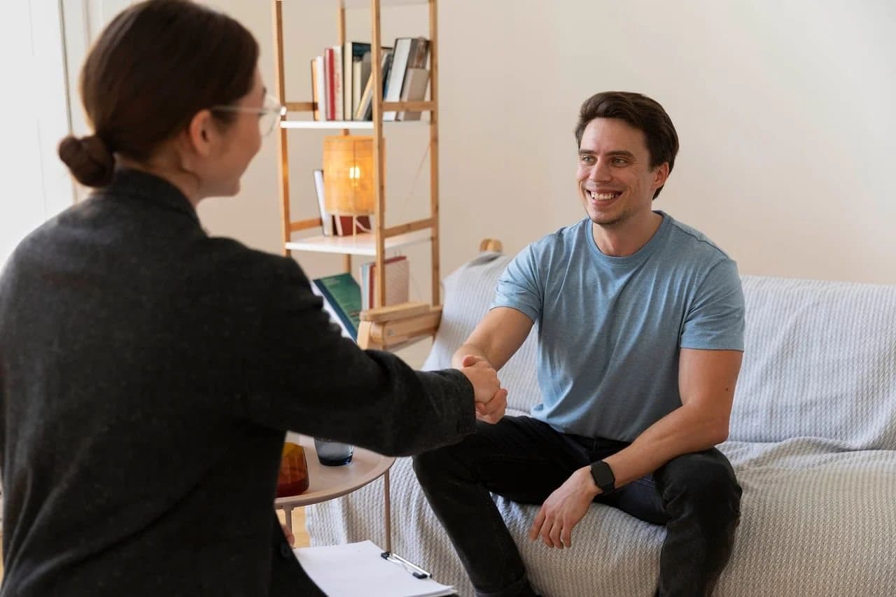 A health insurance agent shaking hands with a client during a consultation